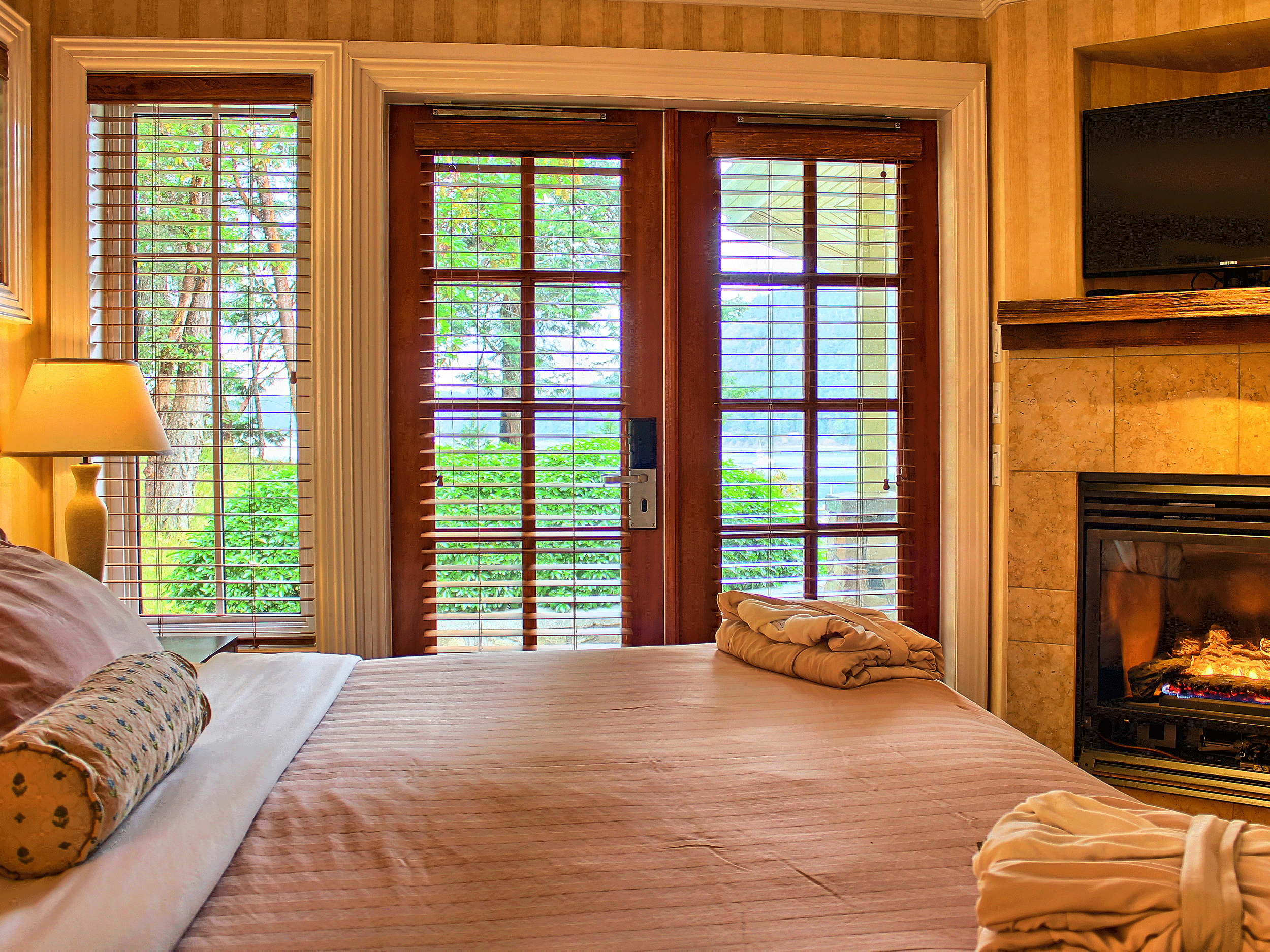 pink bed in yellow room with fireplace
