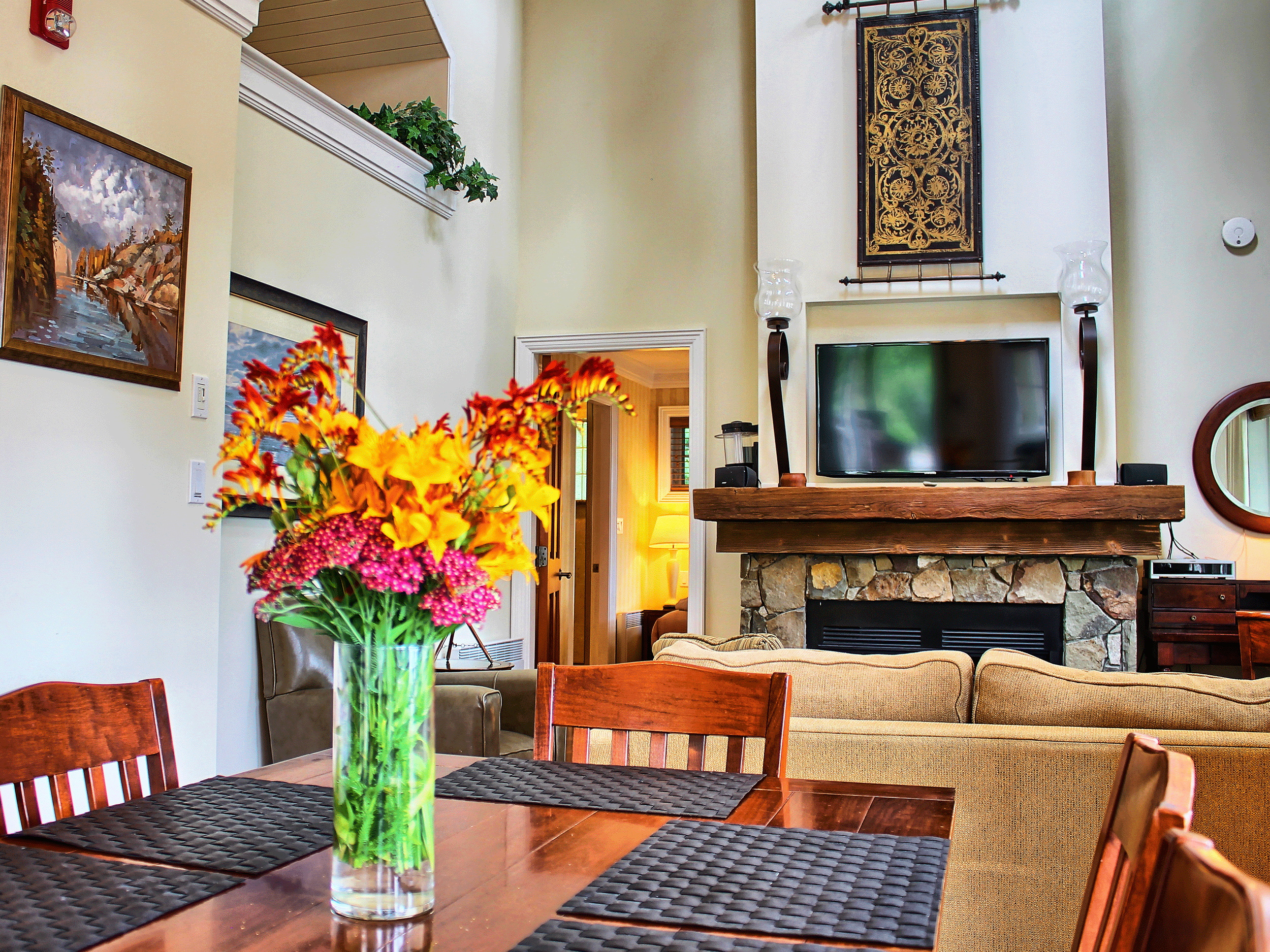 kitchen table with flowers and view of television on fireplace