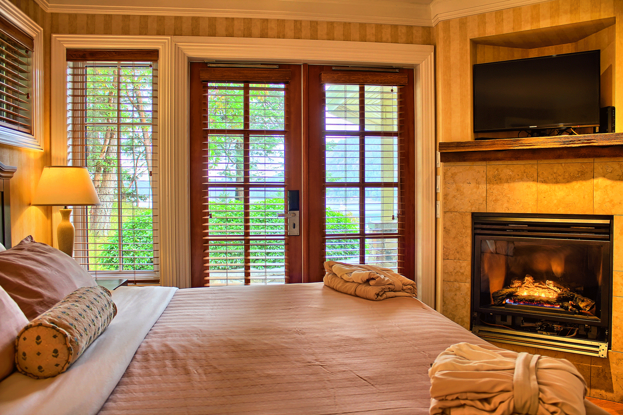 bed next to fireplace and doors to the outside