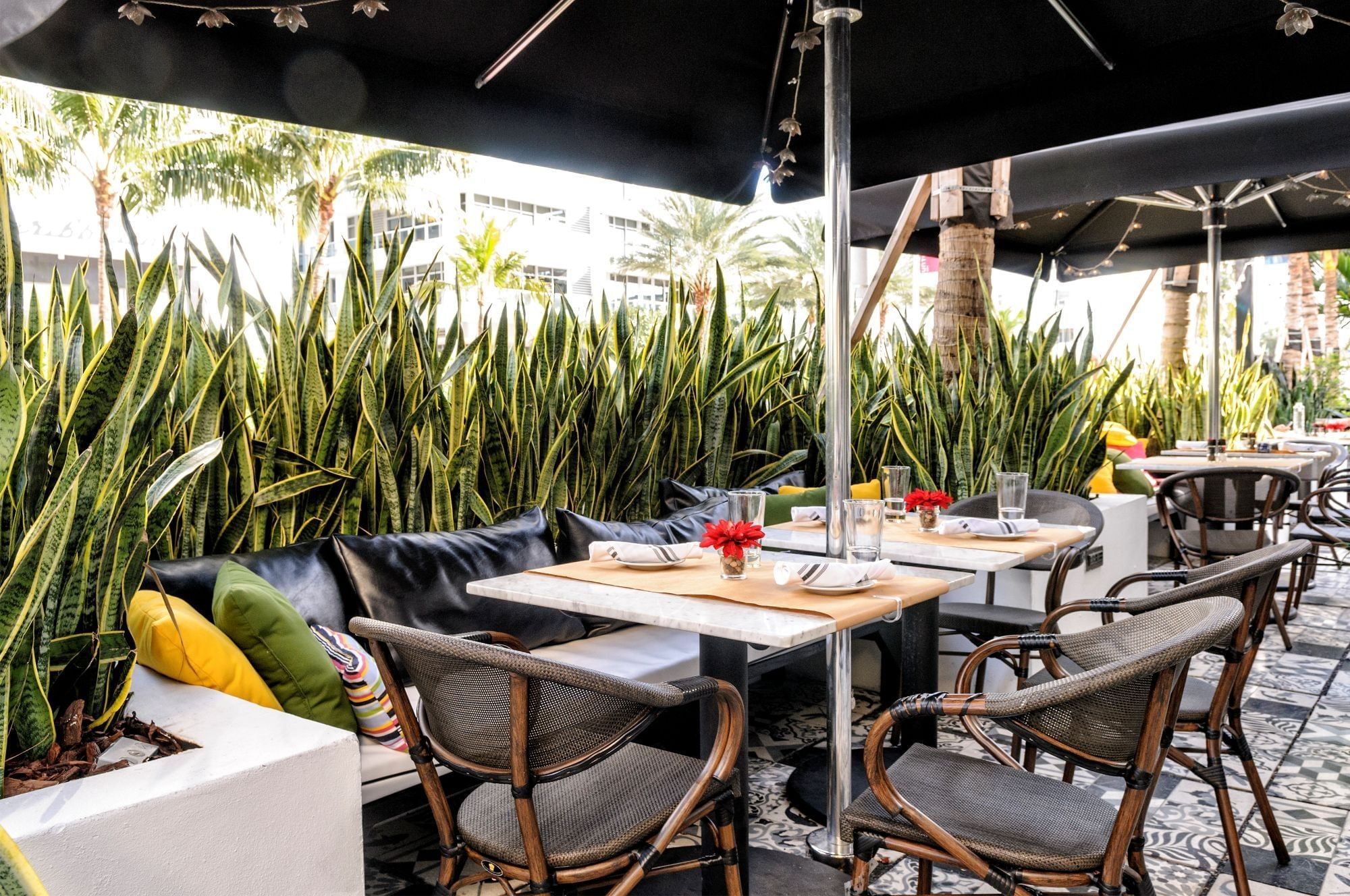 an outdoor dining area with tables and chairs under black umbrellas