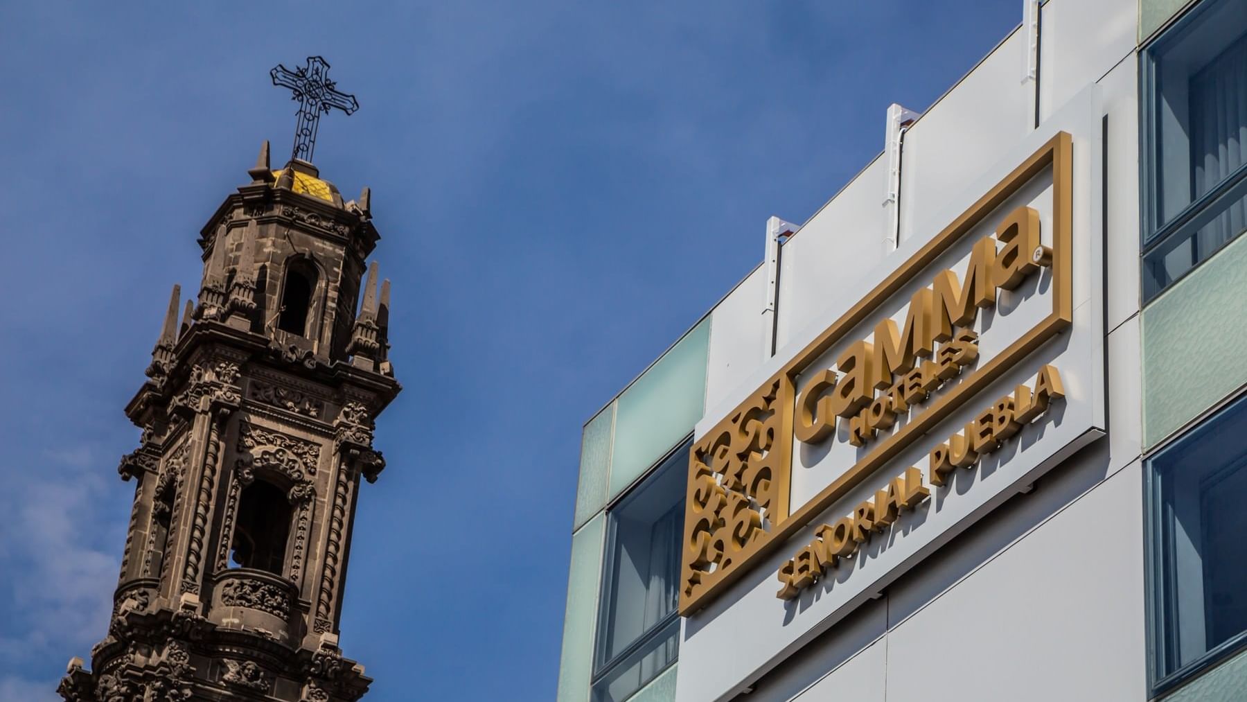 Hotel exterior with sign featuring the official logo of Gamma Hotels Senorial Puebla & view of the nearby Cathedral