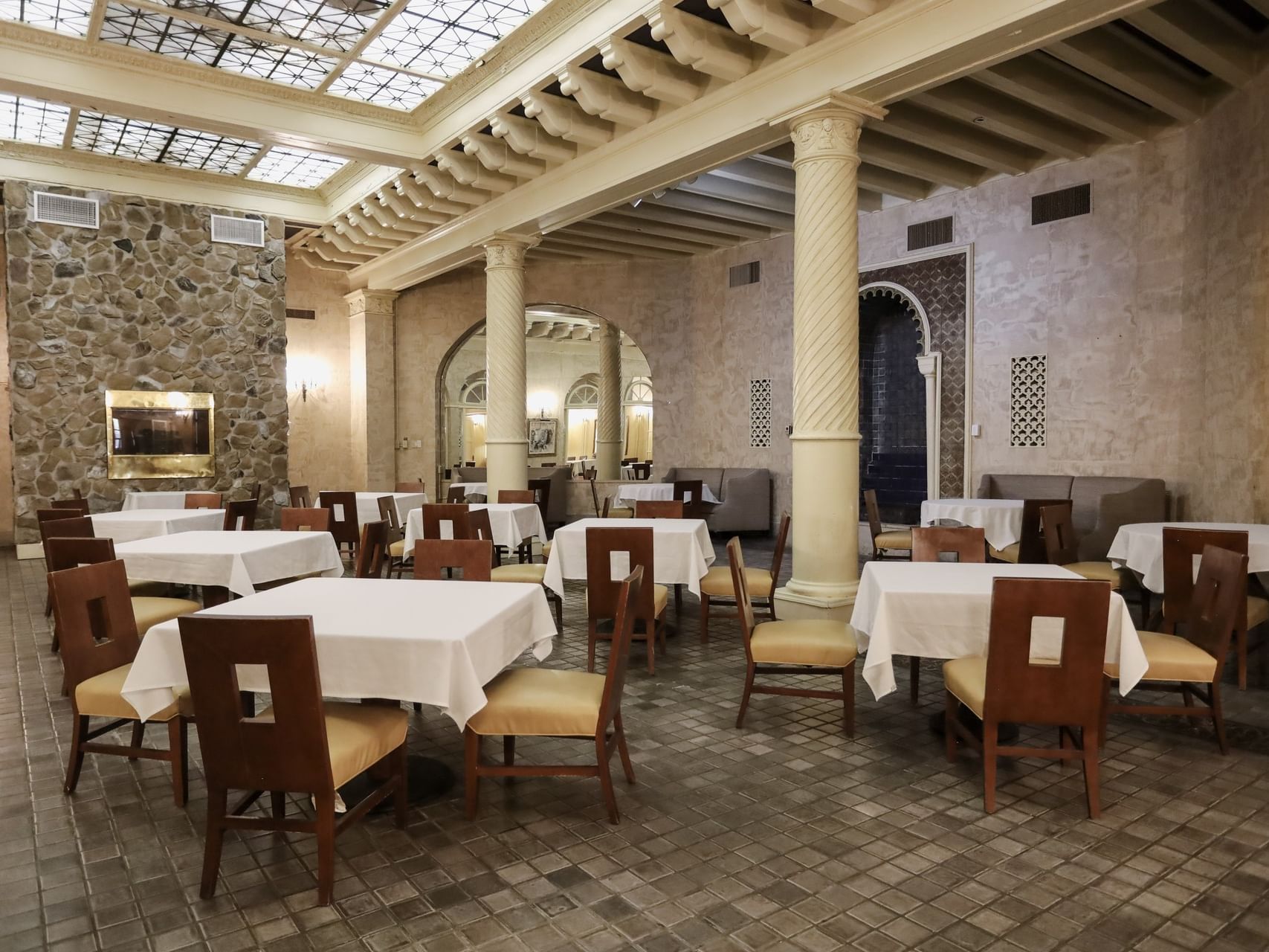 Bright dining area in Fountain Room with white tables, stone fireplace and tall pillars at Arlington Resort Hotel & Spa