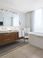 Penthouse René-Lévesque bathroom featuring a wood vanity with a mirror by the bathtub at Warwick Le Crystal Montreal