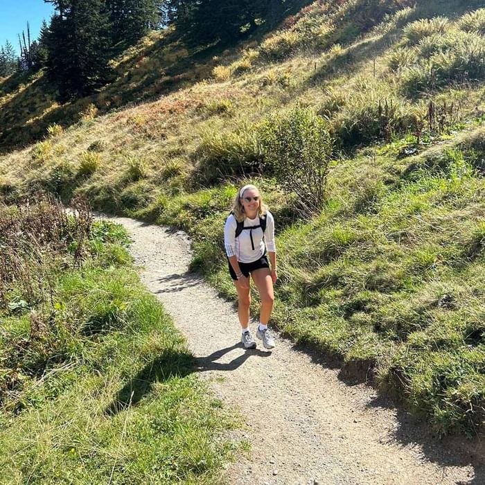 Frau wandert auf Bergpfad umgeben von grüner Vegetation bei Falkensteiner Hotel Montafon