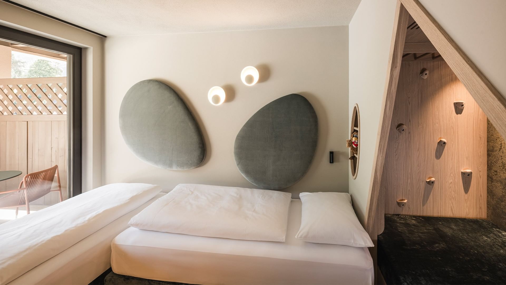 Modernes Zimmer mit zwei Betten, einzigartiger Wandgestaltung und angrenzendem Kletterbereich.