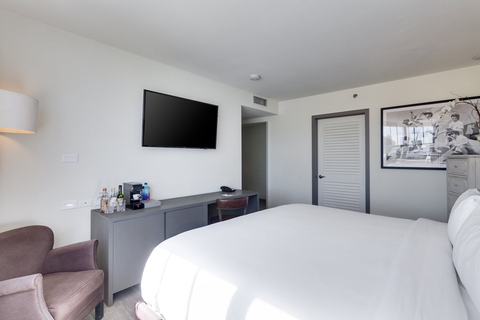 A hotel room with a large bed, TV, desk, and chair.