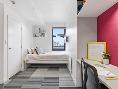 Clean bedroom with desk, bed, and window at UniLodge Auckland City.