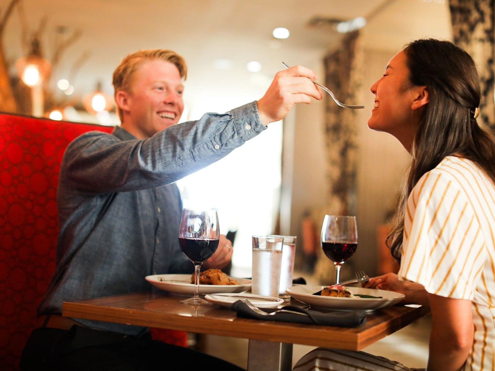 A couple dining in Cora's Restaurant at The White House Hotel, sharing a delicious meal and red wine in a romantic setting