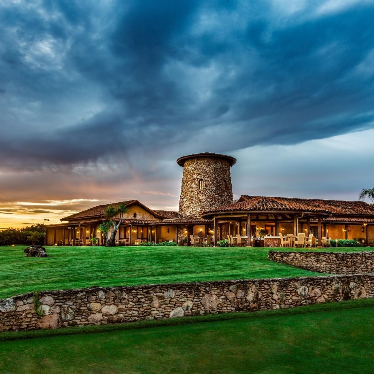 Stone tower restaurant with terrace seating on manicured lawn under dramatic sunset sky for Halloween at La Casa Restaurant.