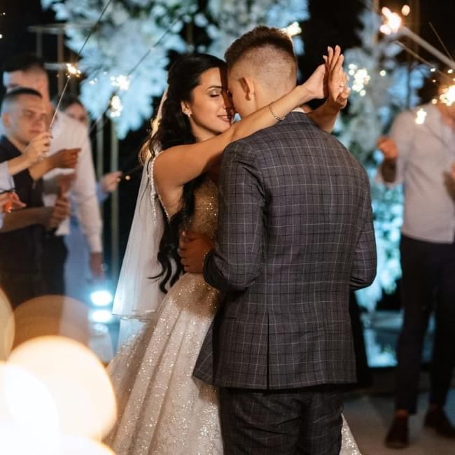 Bride and groom surrounded by guests with sparklers featuring our blog on 