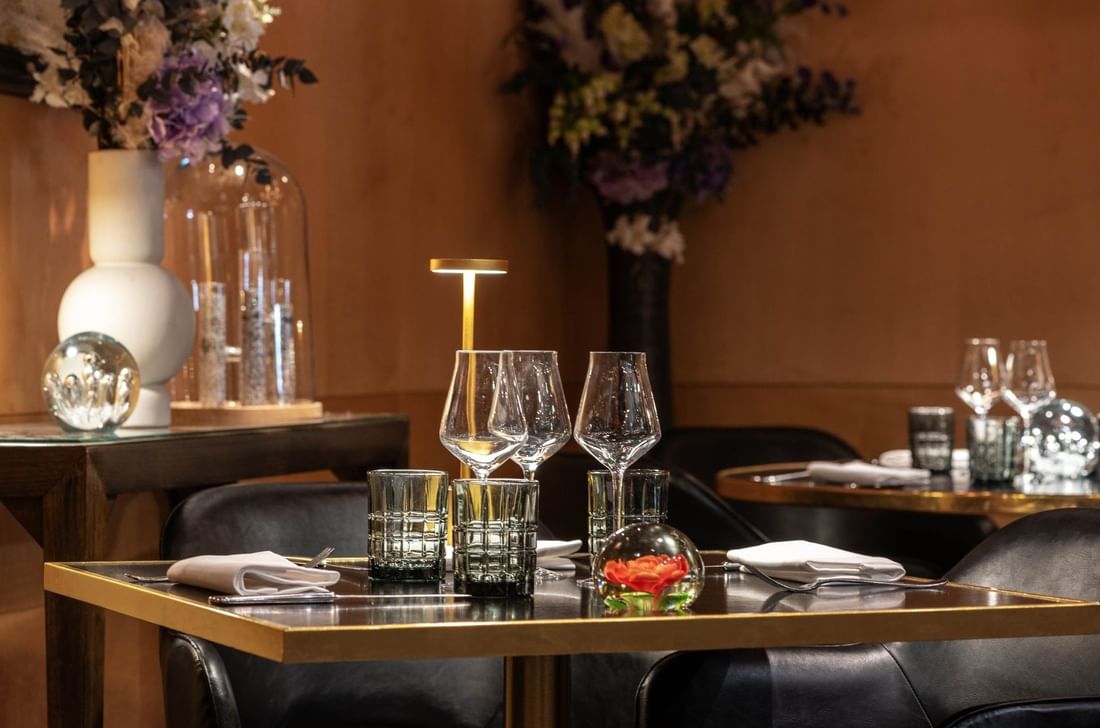 Wine glasses on a black table by leather chairs at Warwick Paris Champs Elysées