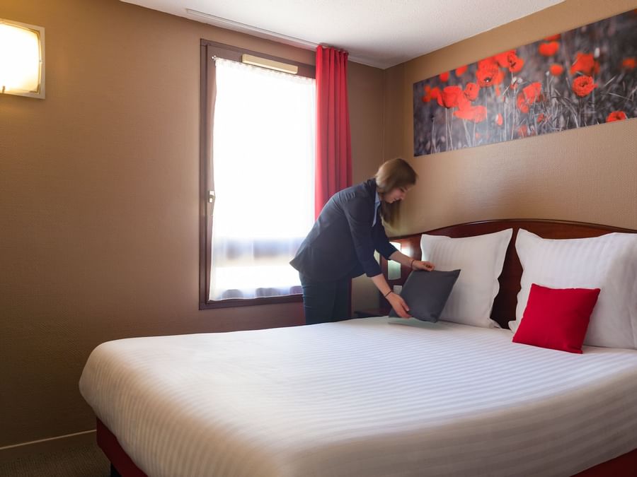 A maid preparing a bed in a room at Hotel Arras