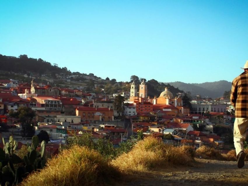 Hombre contemplando un encantador pueblo en colina con edificios coloridos cerca de Real Inn
