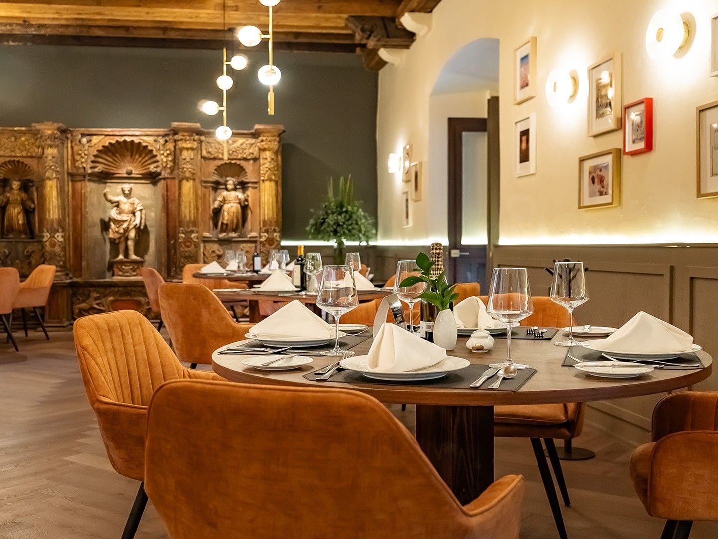 Elegant restaurant table with white linens, wine glasses, and orange velvet chairs in Tierra Mia at Quinta Real Puebla