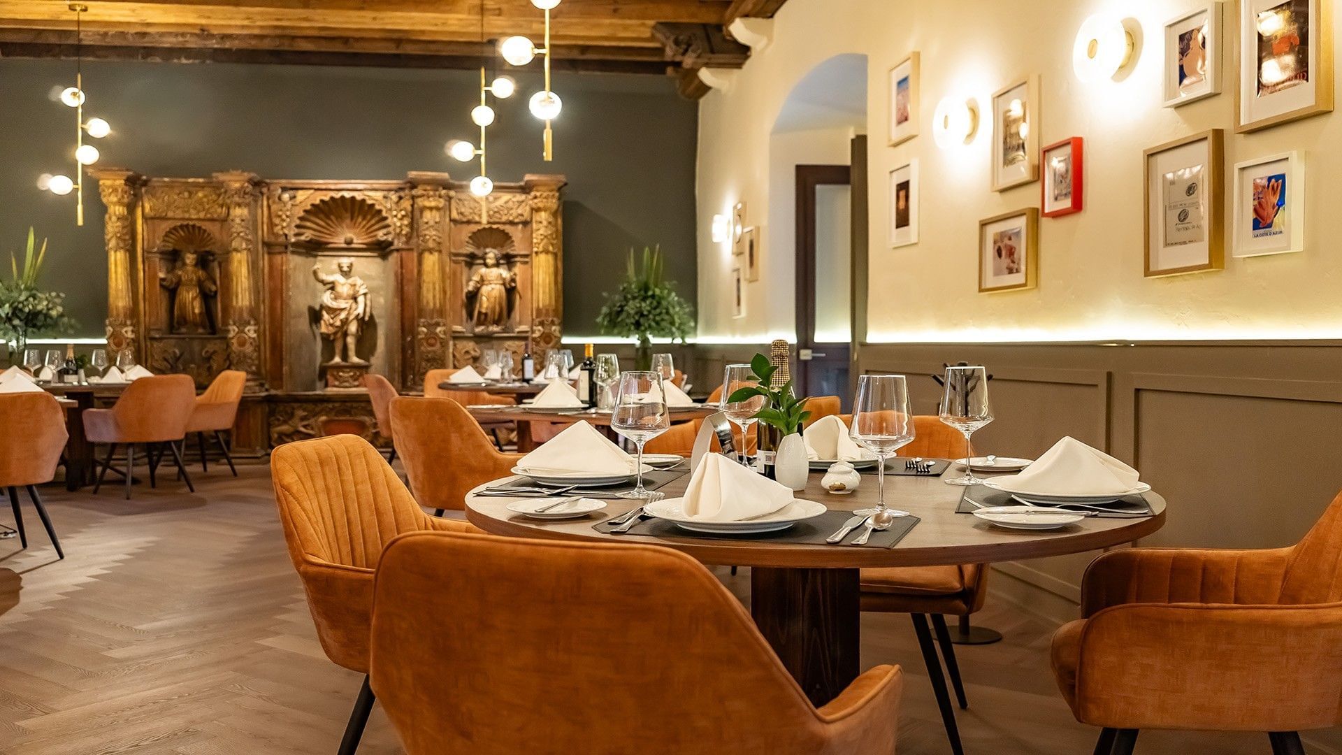 Elegant restaurant table with white linens, wine glasses, and orange velvet chairs in Tierra Mia at Quinta Real Puebla