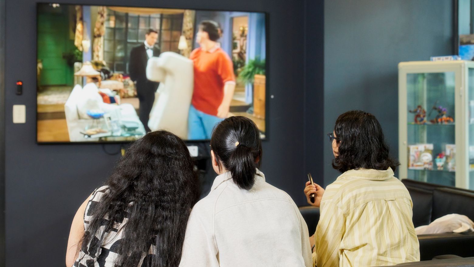Three residents watching TV in a common area at Student Living - 800 Swanston.