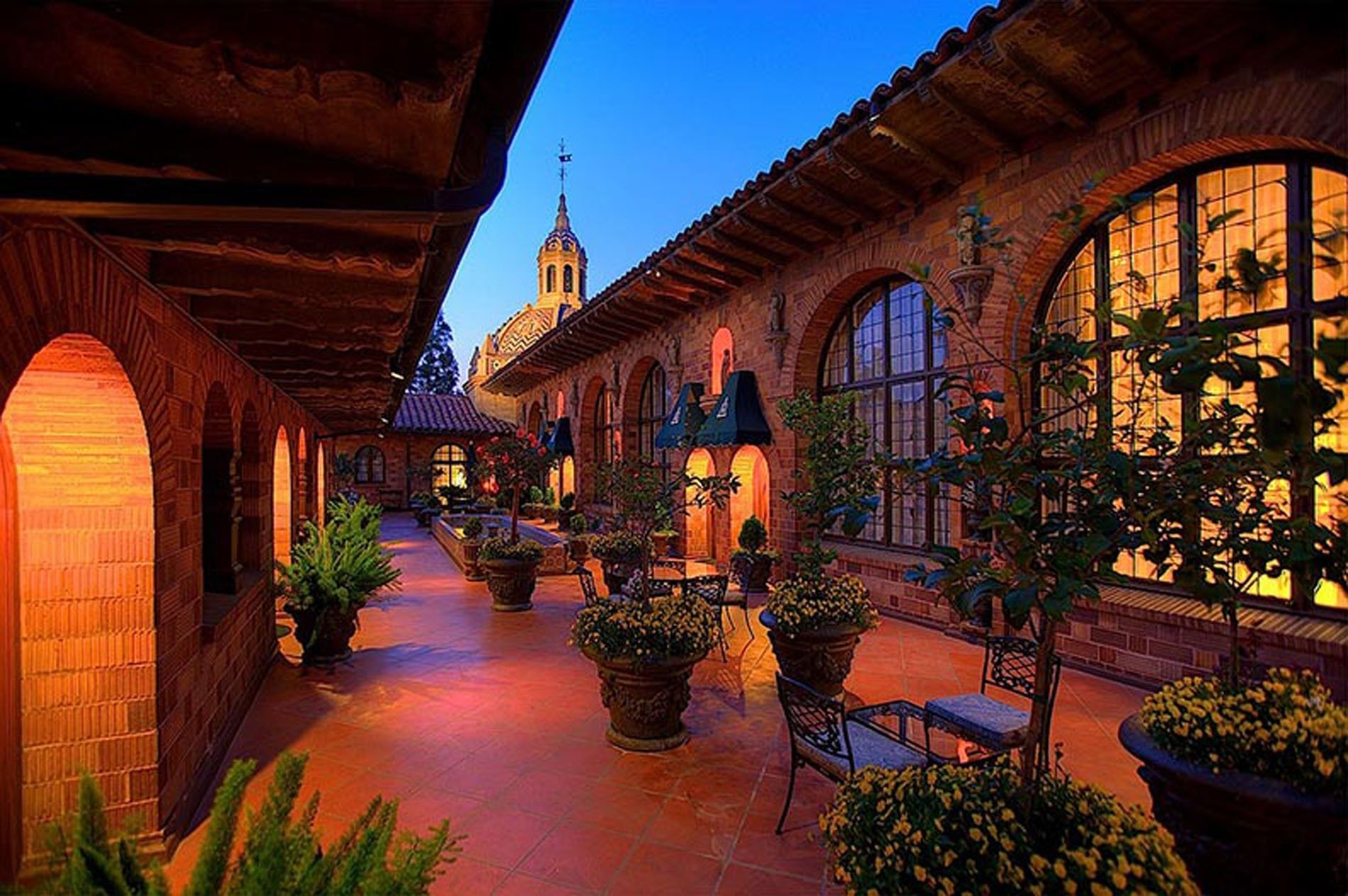 Historic Mission Inn courtyard at twilight with warm lights, potted plants, and arched walkways near Kelly's Spa
