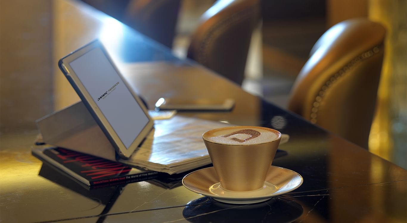 Workspace with a cup of coffee on the table next to an open e-reader and book at DAMAC Maison Mall Street