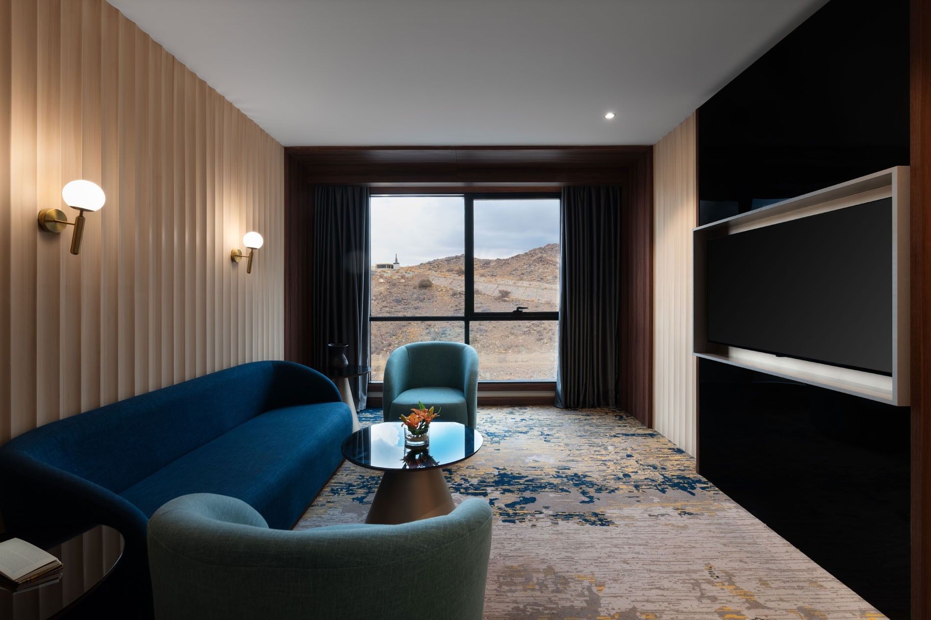 TV lounge with plush sofa by the window in Junior Suite at Warwick Al Taif Hotel