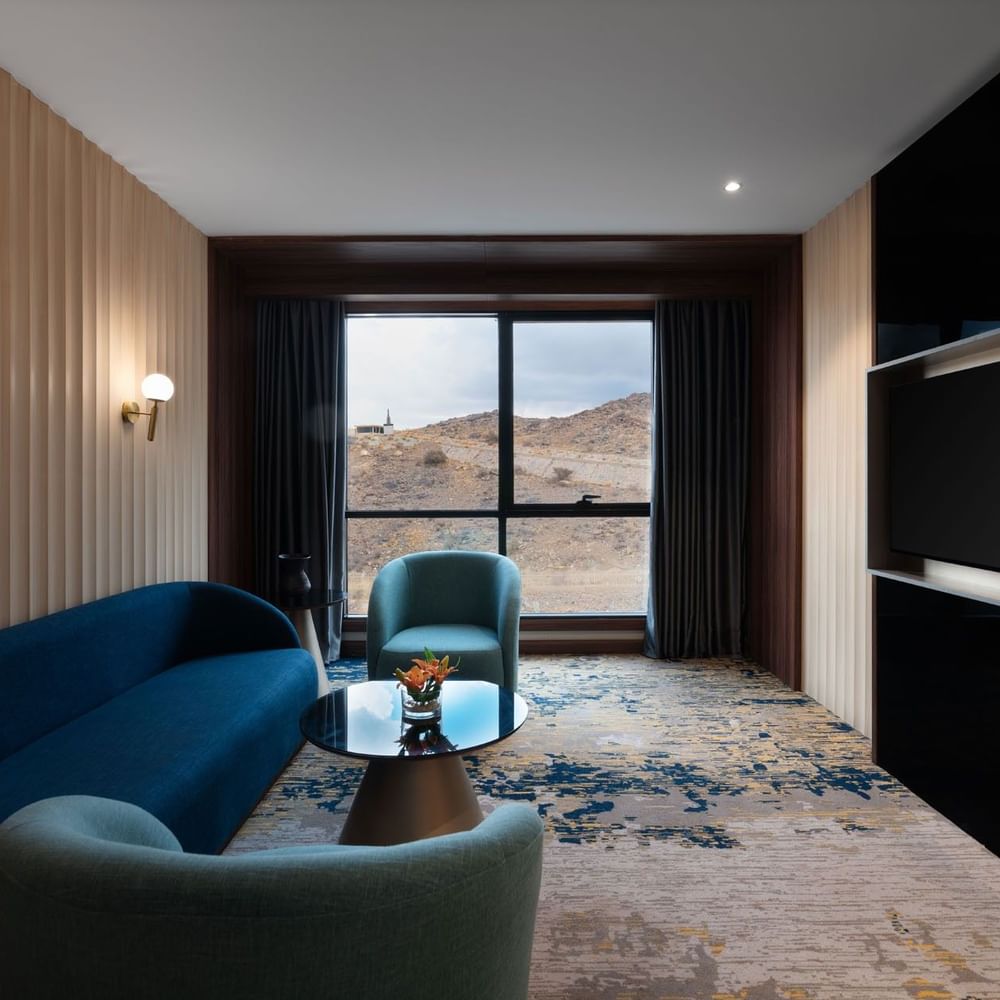 TV lounge with plush sofa by the window in Junior Suite at Warwick Al Taif Hotel