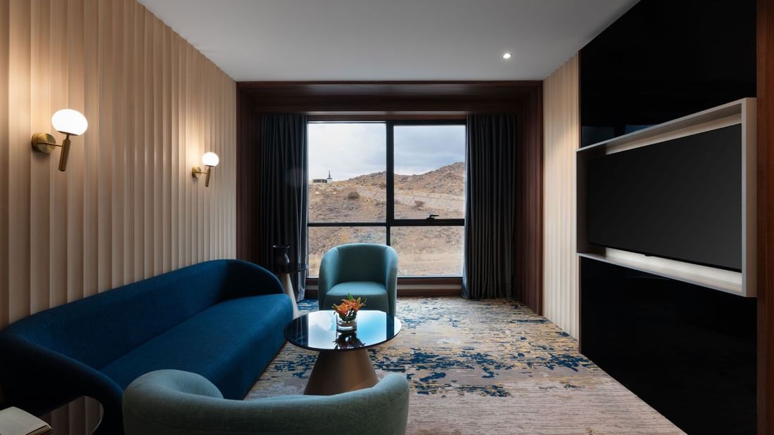 TV lounge with plush sofa by the window in Junior Suite at Warwick Al Taif Hotel