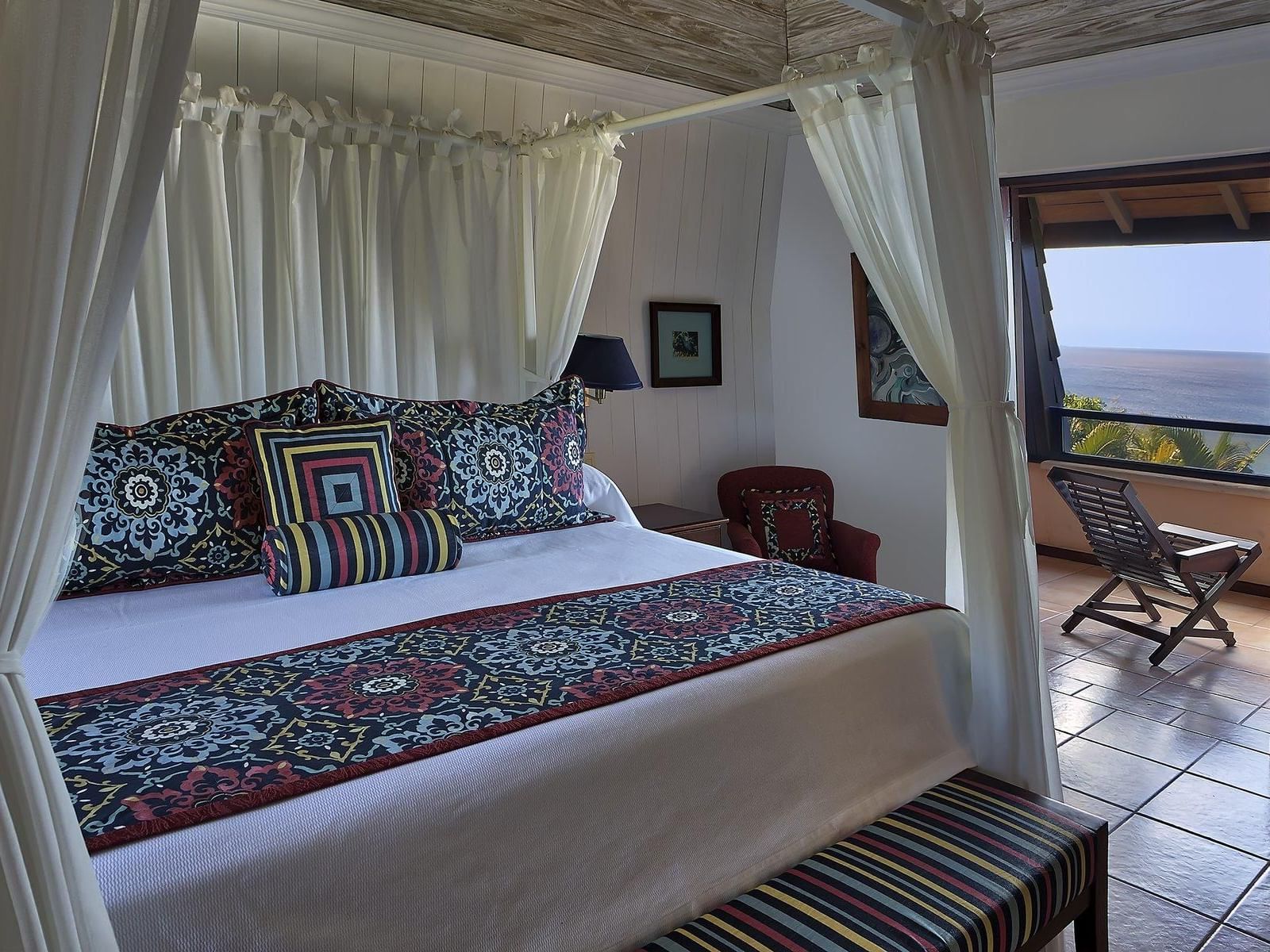 bed in villa with balcony overlooking ocean