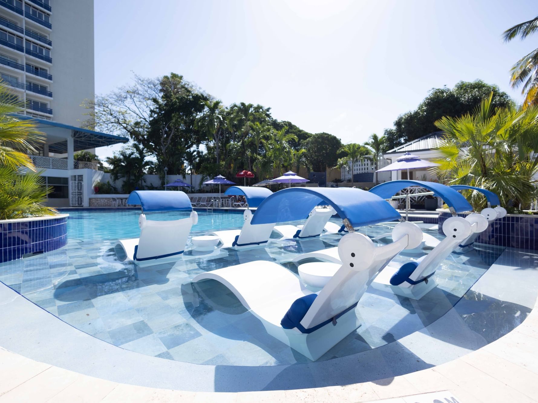 Outdoor pool with sun loungers by  Pool Bar & Lounge at Jamaica Pegasus Hotel