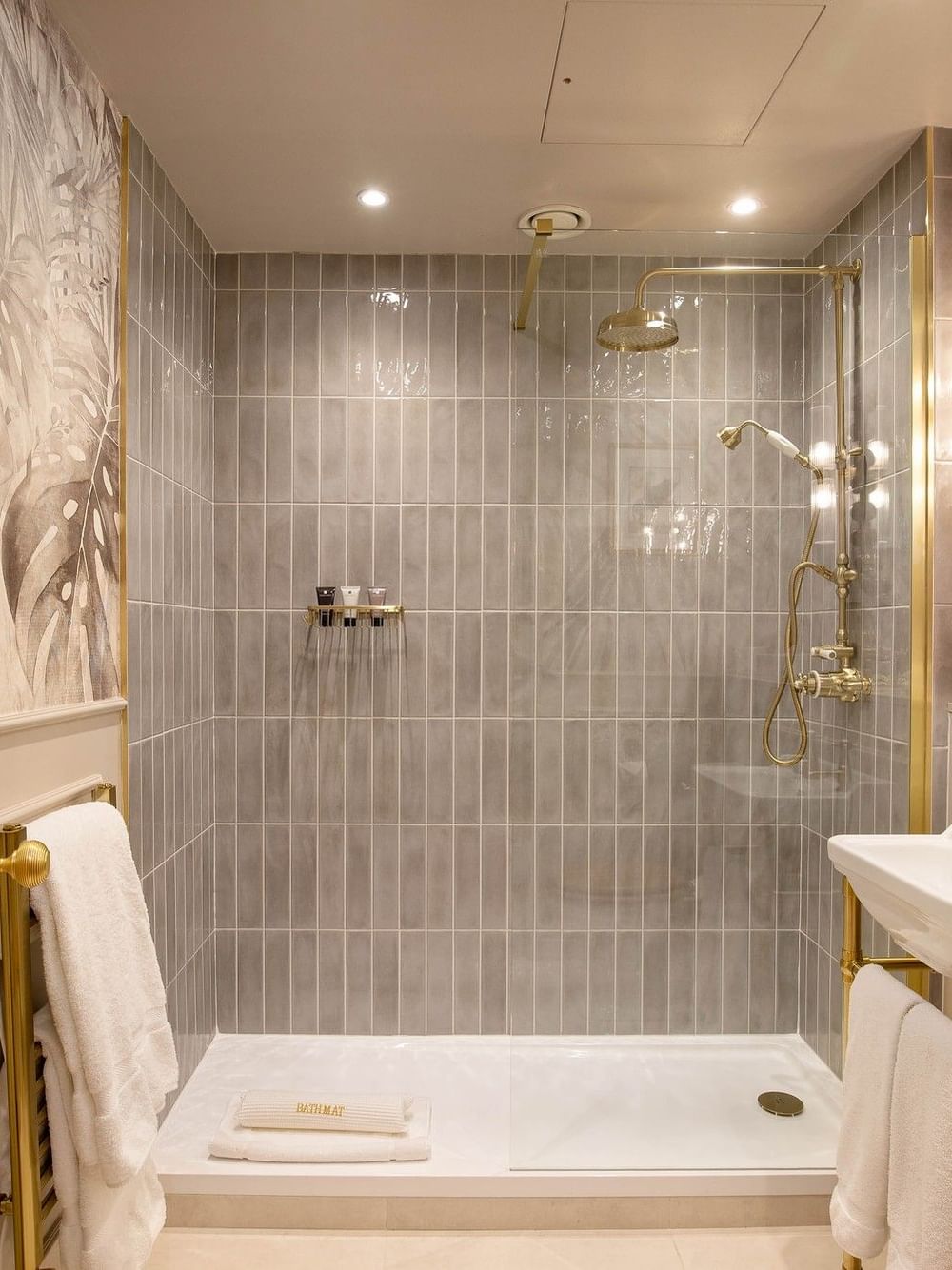 Salle de bain élégante avec douche, lavabo double et miroir décoratif.