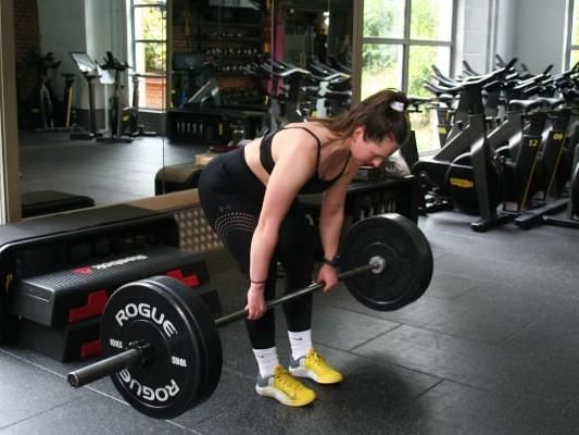 Women picking up a set of weights in total glue class at East Park Gym in Wokingham