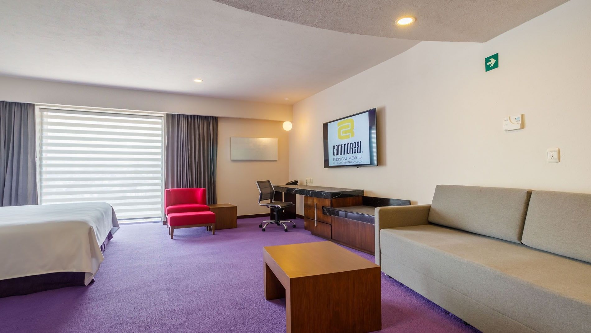 King Junior Suite with purple carpet, a red chair, and a large TV on the wall at Camino Real Pedregal Mexico