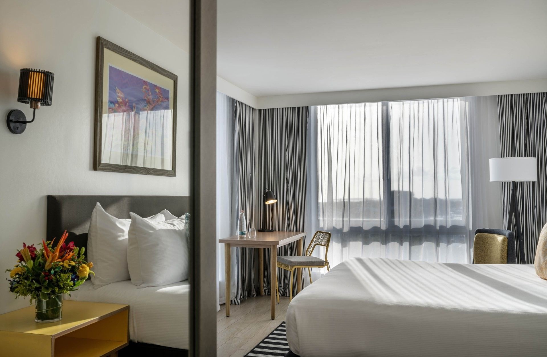 White bed by a wooden desk with a black lamp under a framed painting in Water View at Warwick Paradise Island Bahamas