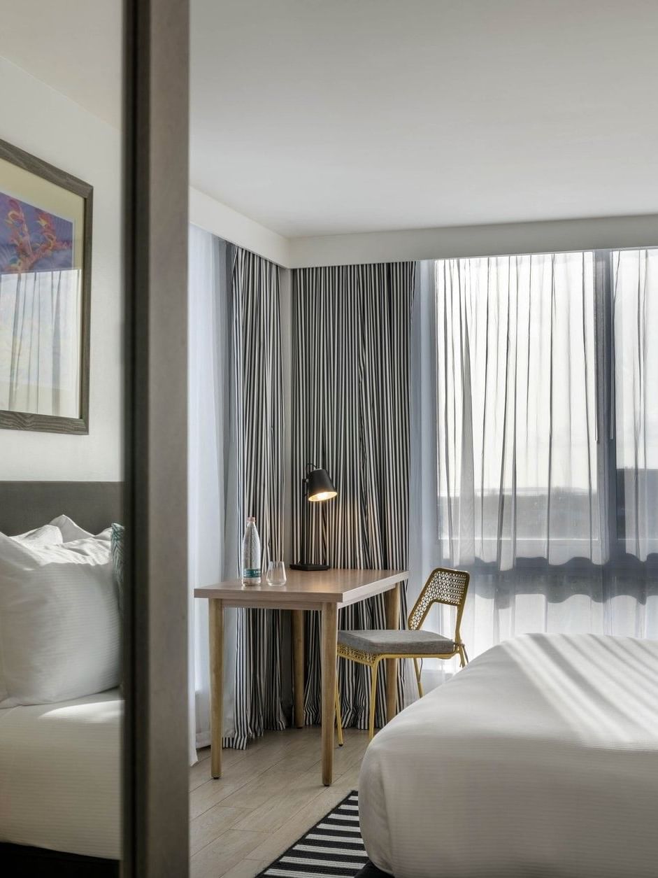 White bed by a wooden desk with a black lamp under a framed painting in Water View at Warwick Paradise Island Bahamas