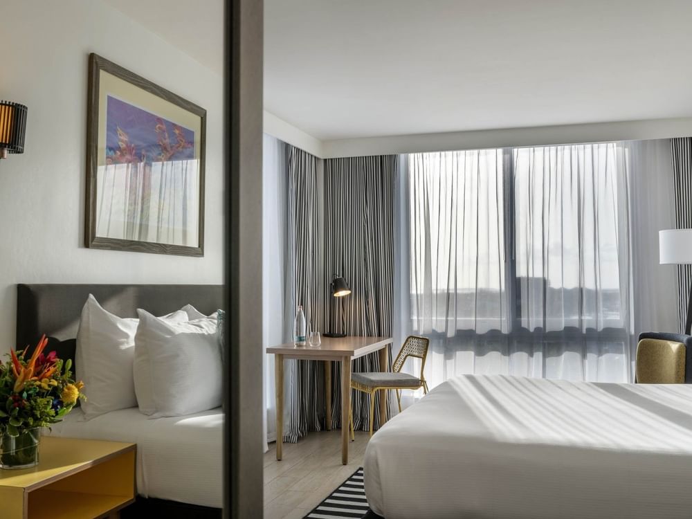 White bed by a wooden desk with a black lamp under a framed painting in Water View at Warwick Paradise Island Bahamas