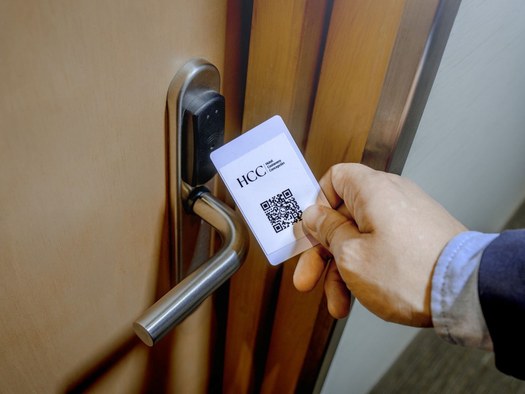 Persona que utiliza una tarjeta magnética HCC con código QR para abrir una puerta.