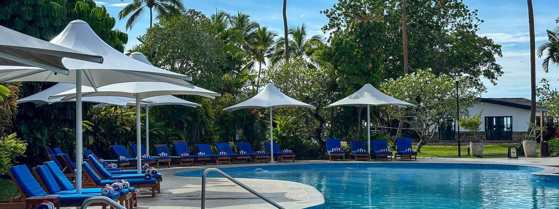 Outdoor swimming pool with lounge chairs and umbrellas at The Naviti Resort in Korolevu