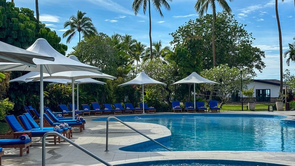 Outdoor swimming pool with lounge chairs and umbrellas at The Naviti Resort in Korolevu.