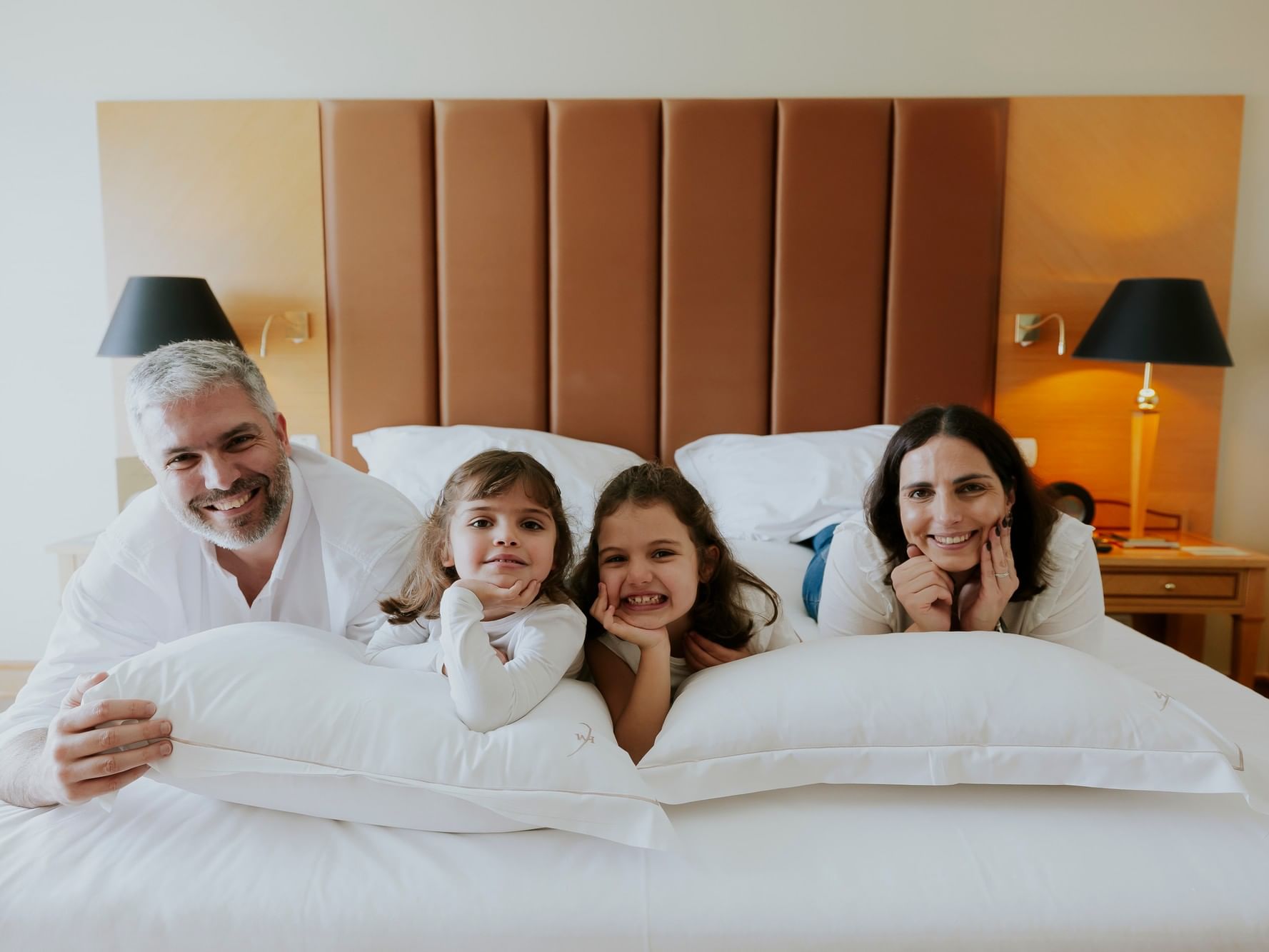 Famille heureuse sur un lit avec l'offre Moments en Famille.