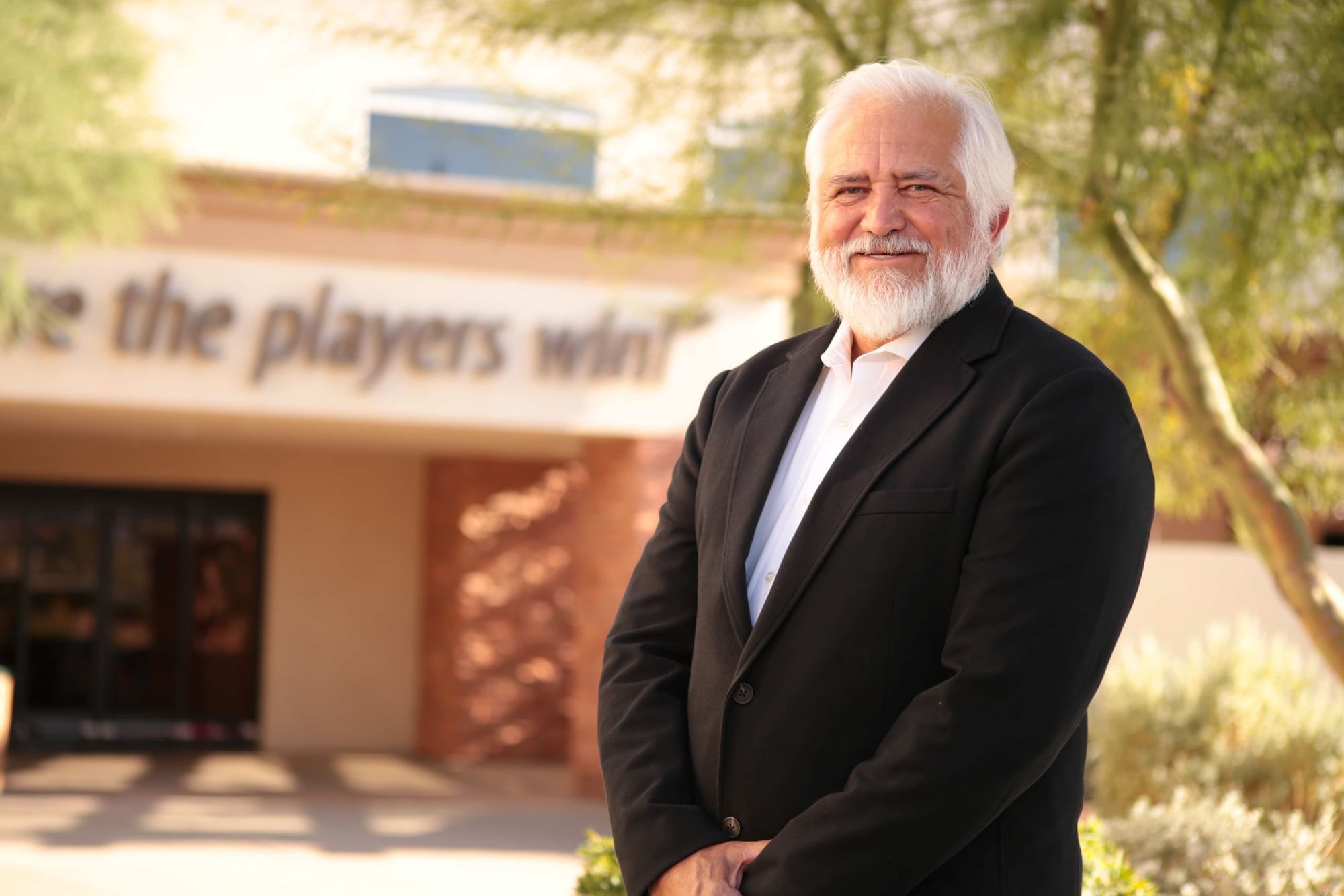 Smiling executive in black suit jacket standing outdoors near entrance with signage at Eureka Casino Resort