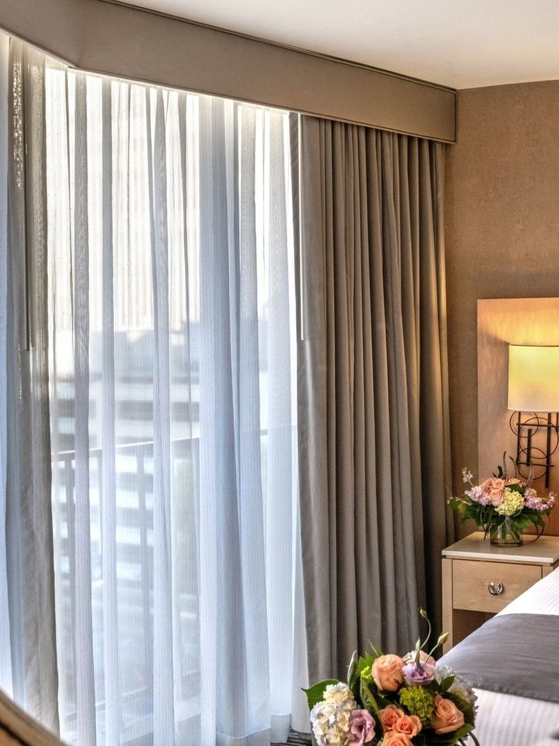 Circular mirror by a bed and flowers reflecting a window with sheer drapes in Executive Room at Warwick Seattle