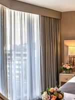 Circular mirror by a bed and flowers reflecting a window with sheer drapes in Executive Room at Warwick Seattle