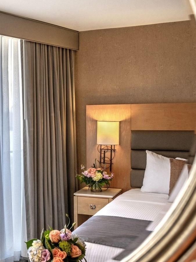 Mirror reflecting an Executive Room features a bed, flowers, and a window at Warwick Seattle