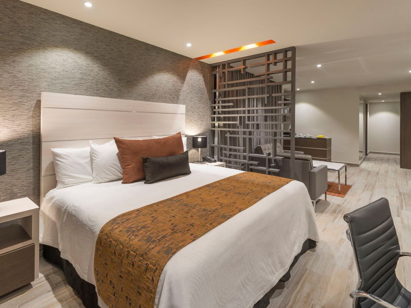 King Long Stay Suite featuring a king bed, decorative room divider, and a comfortable seating area at Real Inn Celaya