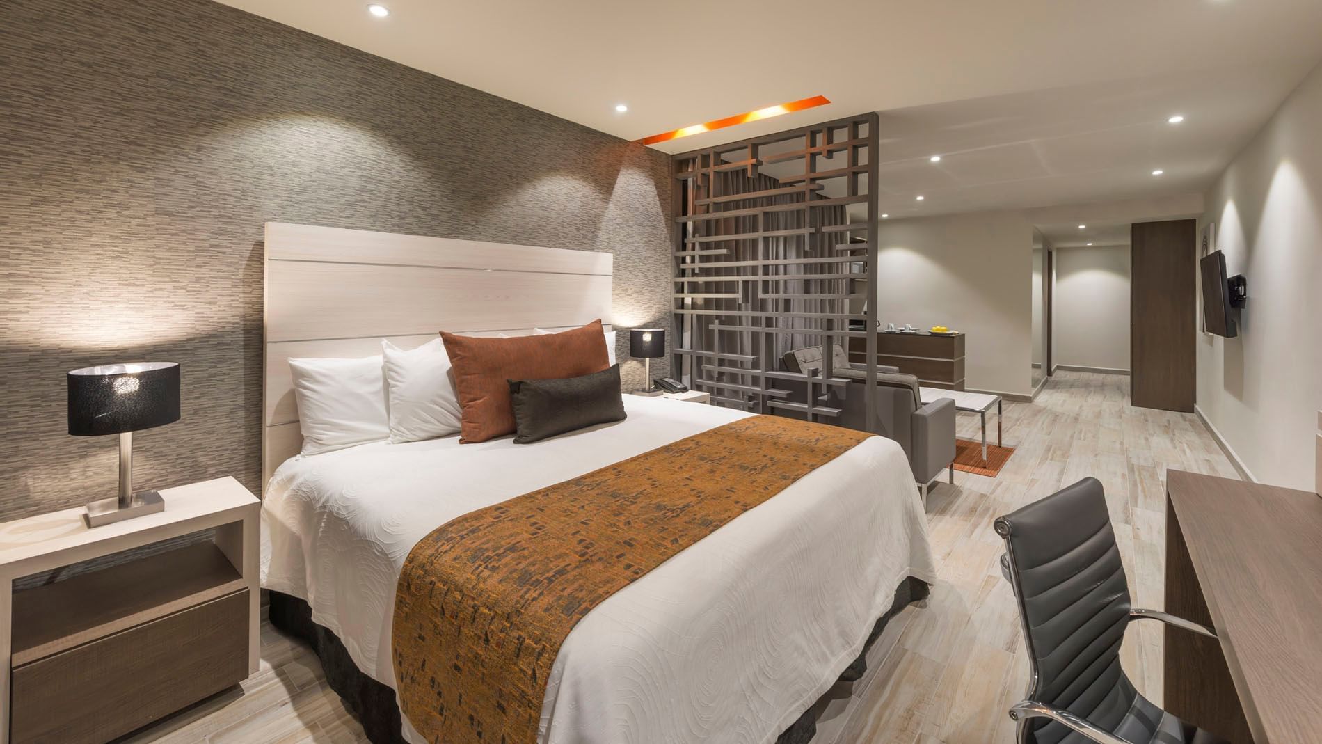 King Long Stay Suite featuring a king bed, decorative room divider, and a comfortable seating area at Real Inn Celaya