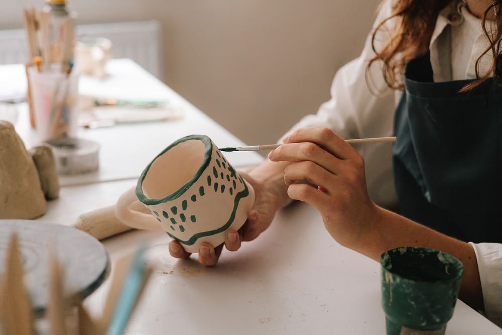 Hands painting a ceramic mug during a creative workshop experience at Hotel Barsey by Warwick