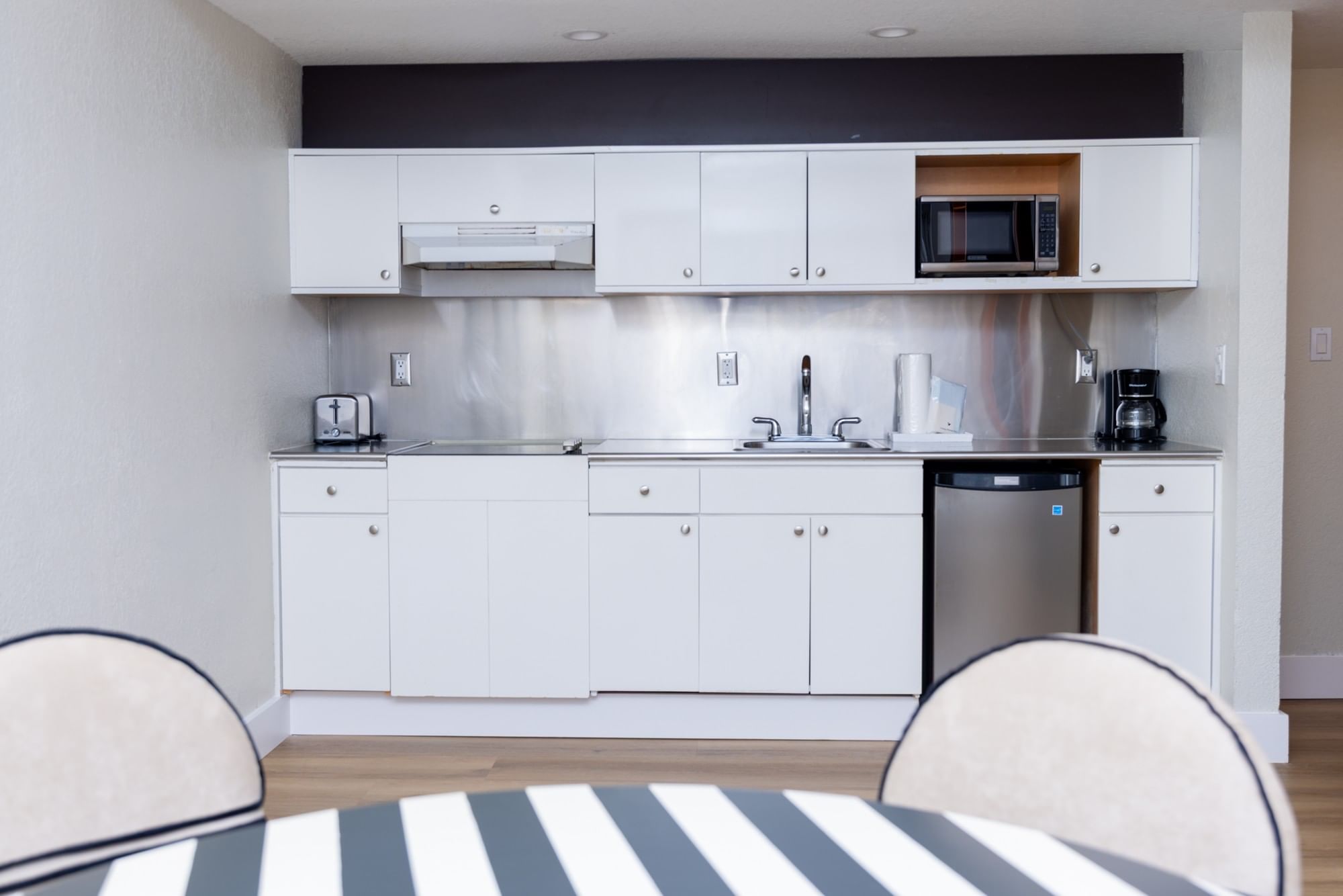 A kitchenette with white cabinets and stainless steel appliances.