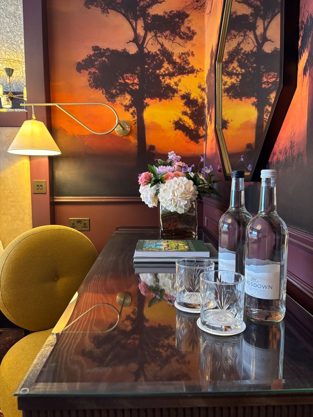Table with flowers, two bottles, and glasses in an Executive Room at The Capital Hotel, Apartments & Townhouse