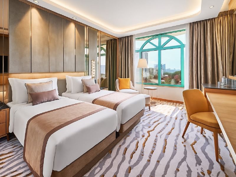 Two beds with a seating area by the window in the Twin Deluxe Room at Sunway Resort