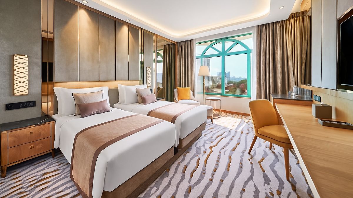 Two beds with a seating area by the window in the Twin Deluxe Room at Sunway Resort