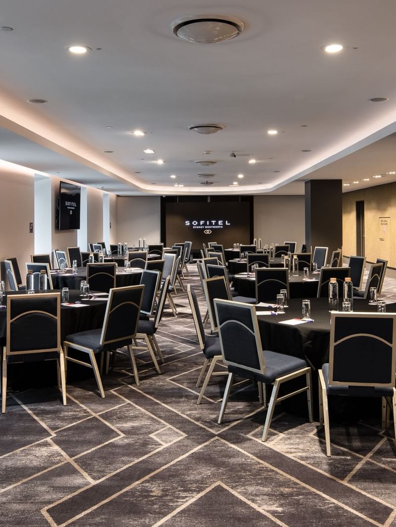 Adelaide room meeting space with round tables, black chairs and modern conference setup