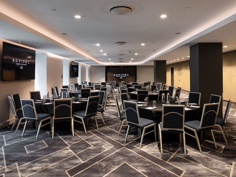 Adelaide room meeting space with round tables, black chairs and modern conference setup